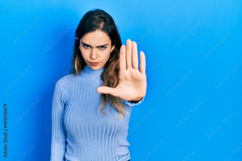 Fototapeta premium Young hispanic girl wearing casual clothes doing stop sing with palm of the hand. warning expression with negative and serious gesture on the face.