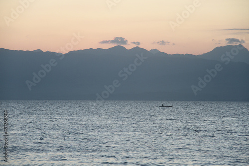 Silhouette of fisherman on fishing boat during sunset.