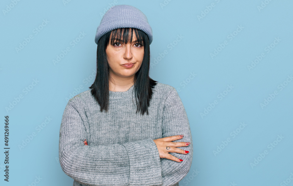 Young hispanic woman wearing cute wool cap skeptic and nervous, disapproving expression on face with crossed arms. negative person.