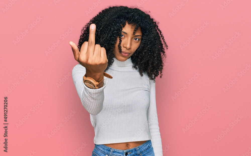 Young african american girl wearing casual clothes showing middle finger, impolite and rude fuck off expression Young african american girl wearing casual clothes showing middle finger, impolite and rude fuck off expression