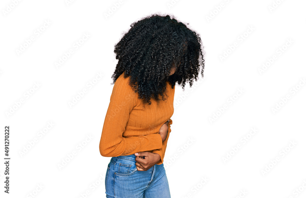 Young african american girl wearing casual clothes with hand on stomach because nausea, painful disease feeling unwell. ache concept. Young african american girl wearing casual clothes with hand on stomach because nausea, painful disease feeling unwell. ache concept.