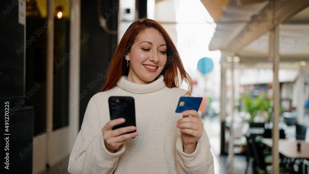 Young redhead woman using smartphone and credit card at street Young redhead woman using smartphone and credit card at street