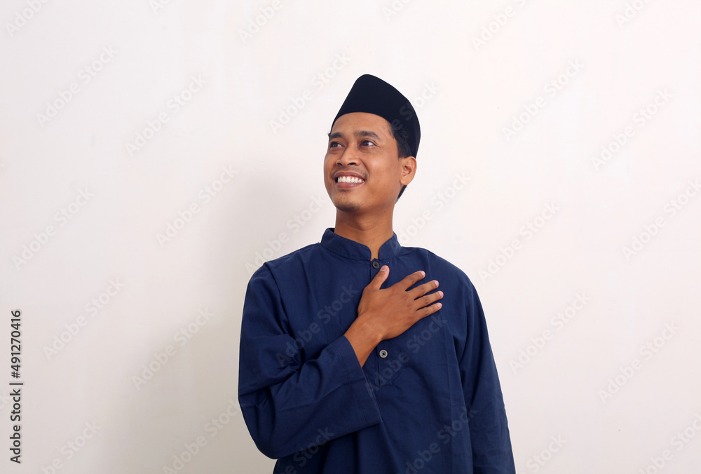 Portrait of happy asian male standing while holding his chest. He is feels relieved. Portrait of happy asian male standing while holding his chest. He is feels relieved.
