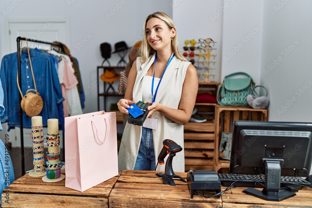 Young blonde woman smiling confident paying with credit card at clothing store Young blonde woman smiling confident paying with credit card at clothing store