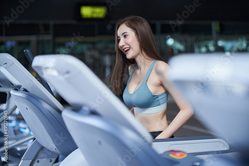A young beautiful woman is having a good time running on a treadmill in fitness center.