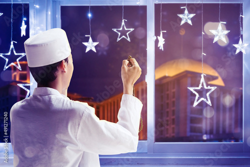 Young man praying to the Allah near the window