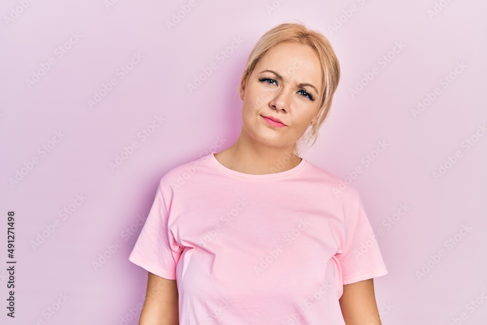 Young blonde woman wearing casual pink t shirt looking sleepy and tired, exhausted for fatigue and hangover, lazy eyes in the morning. Young blonde woman wearing casual pink t shirt looking sleepy and tired, exhausted for fatigue and hangover, lazy eyes in the morning.
