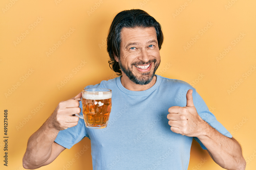 Middle age caucasian man drinking a jar of beer smiling happy and positive, thumb up doing excellent and approval sign Middle age caucasian man drinking a jar of beer smiling happy and positive, thumb up doing excellent and approval sign