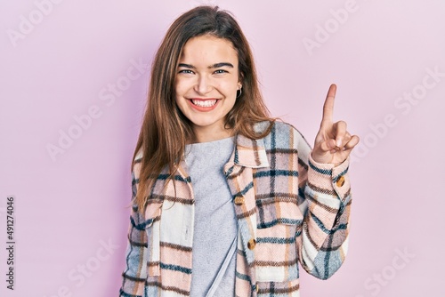 Young caucasian girl wearing casual clothes showing and pointing up with finger number one while smiling confident and happy.