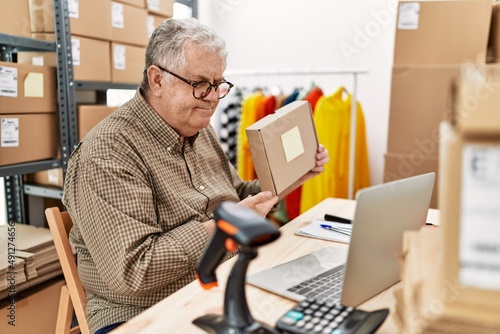 Middle age grey-haired man having video call showing package at storehouse