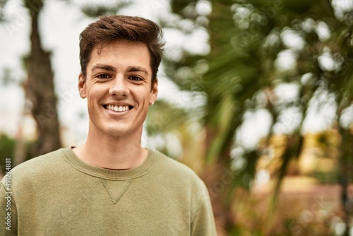 Young hispanic man smiling happy standing at the city.