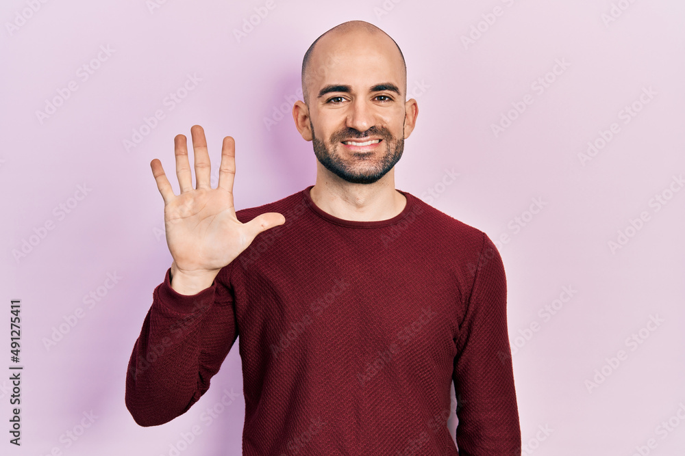 Young bald man wearing casual clothes showing and pointing up with fingers number five while smiling confident and happy. Young bald man wearing casual clothes showing and pointing up with fingers number five while smiling confident and happy.