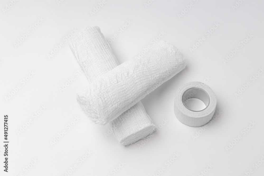 Obraz premium two rolls of bandage and a medical plaster on a white background