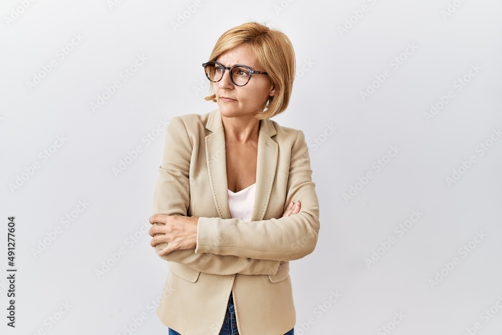 Middle age blonde business woman standing over isolated background looking to the side with arms crossed convinced and confident Middle age blonde business woman standing over isolated background looking to the side with arms crossed convinced and confident