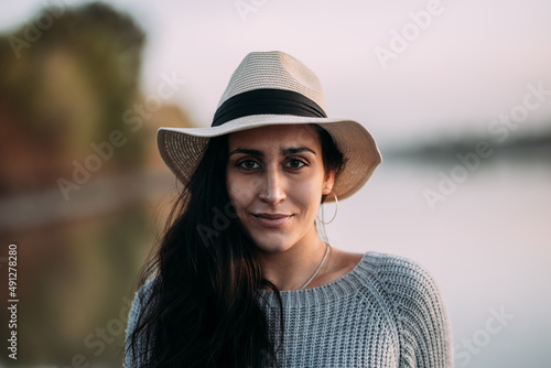 Portrait of a candid woman looking at the camera in a hat by a lake