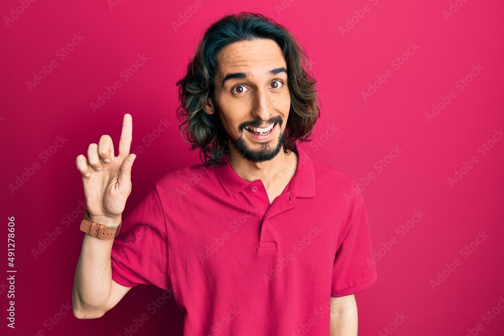 Young hispanic man wearing casual clothes smiling with an idea or question pointing finger up with happy face, number one Young hispanic man wearing casual clothes smiling with an idea or question pointing finger up with happy face, number one