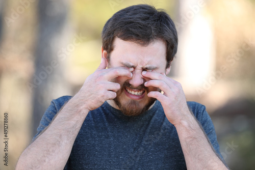 Man scretching itchy eyes in nature