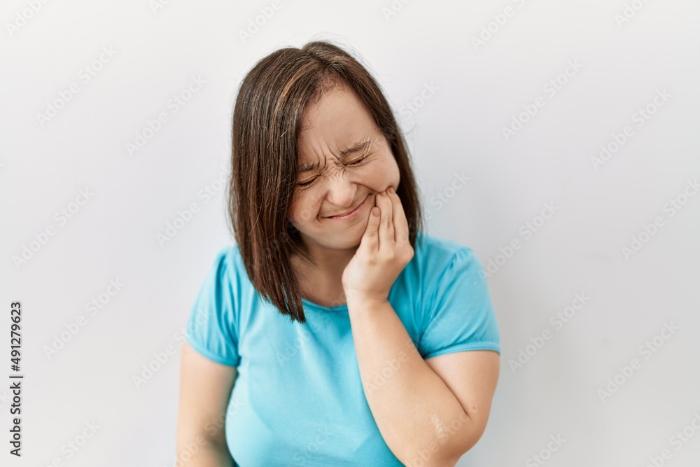 Young down syndrome woman standing over isolated background touching mouth with hand with painful expression because of toothache or dental illness on teeth. dentist Young down syndrome woman standing over isolated background touching mouth with hand with painful expression because of toothache or dental illness on teeth. dentist