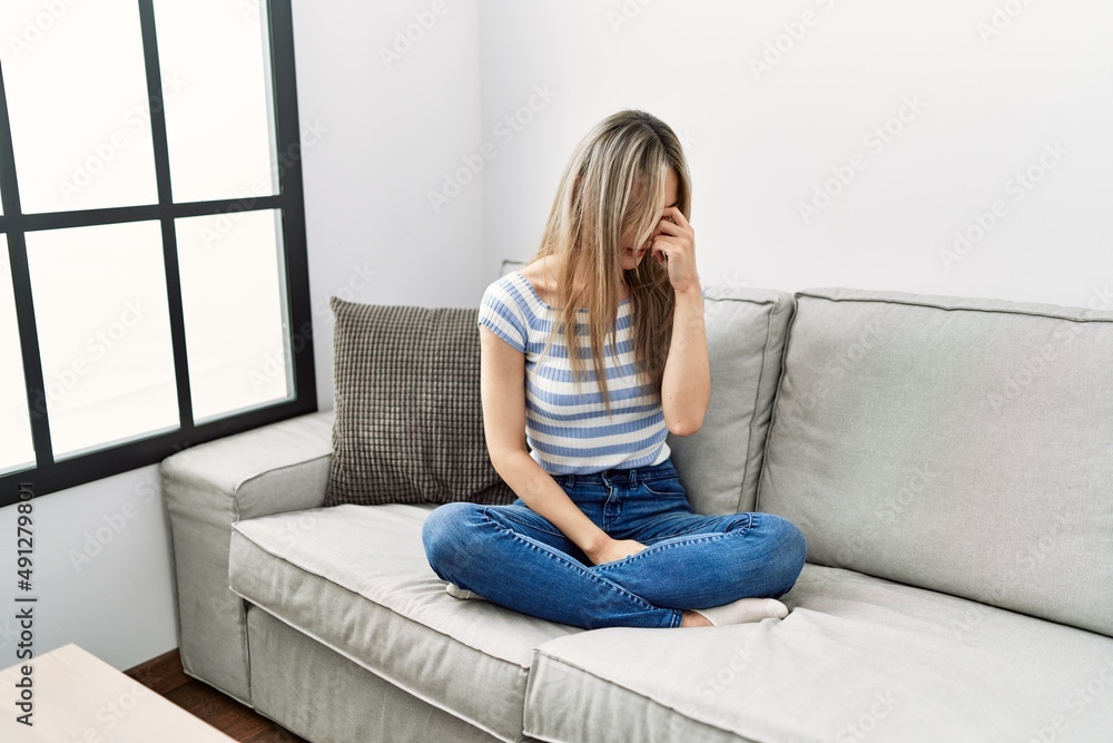 Asian young woman sitting on the sofa at home tired rubbing nose and eyes feeling fatigue and headache. stress and frustration concept. Asian young woman sitting on the sofa at home tired rubbing nose and eyes feeling fatigue and headache. stress and frustration concept.