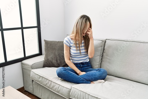 Asian young woman sitting on the sofa at home tired rubbing nose and eyes feeling fatigue and headache. stress and frustration concept.