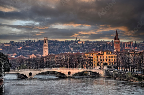 Puente sobre el río Adige en Verona en el atardecer con la ciudad al fondo,  bajo un cielo oscuro invernal. photo
