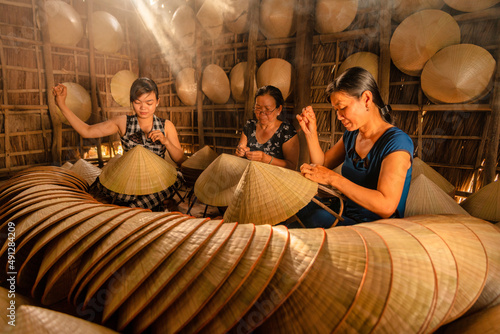 group of vietnamese woman making a traditional conical hat at her home