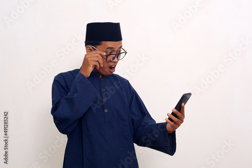 Shocked asian man while looking at his cellular phone. Isolated on white background