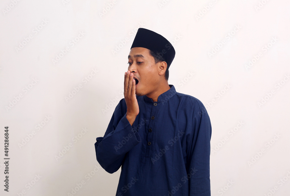 Portrait of funny Asian man yawning and showing a sleepy gesture. Isolated on white background Portrait of funny Asian man yawning and showing a sleepy gesture. Isolated on white background
