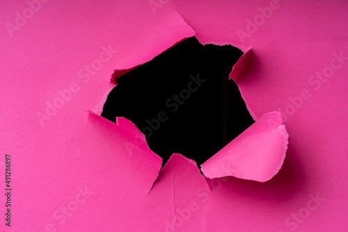 Torn hole in pink paper