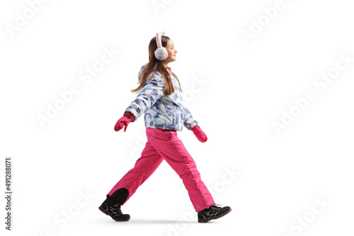 Full length profile shot of a girl wearing winter jacket and pants and walking