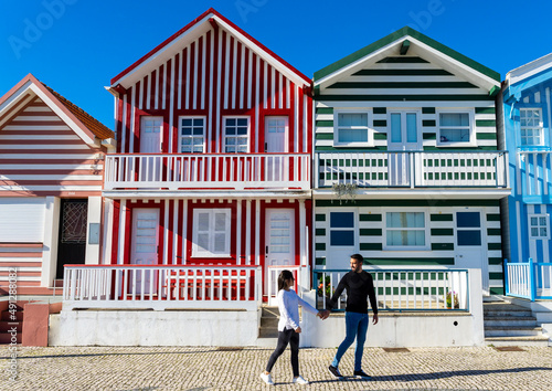 Woman and man strolling on a sightseeing tour of the colorful houses of Costa Nova in Portugal.