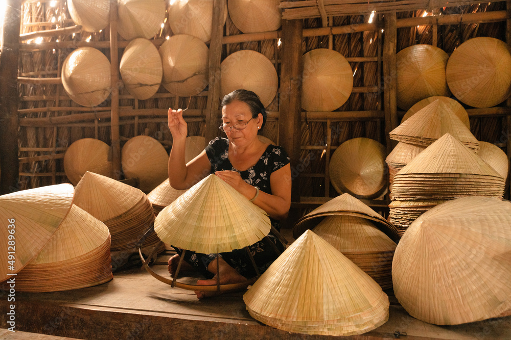 old vietnamese woman making a traditional conical hat at her home