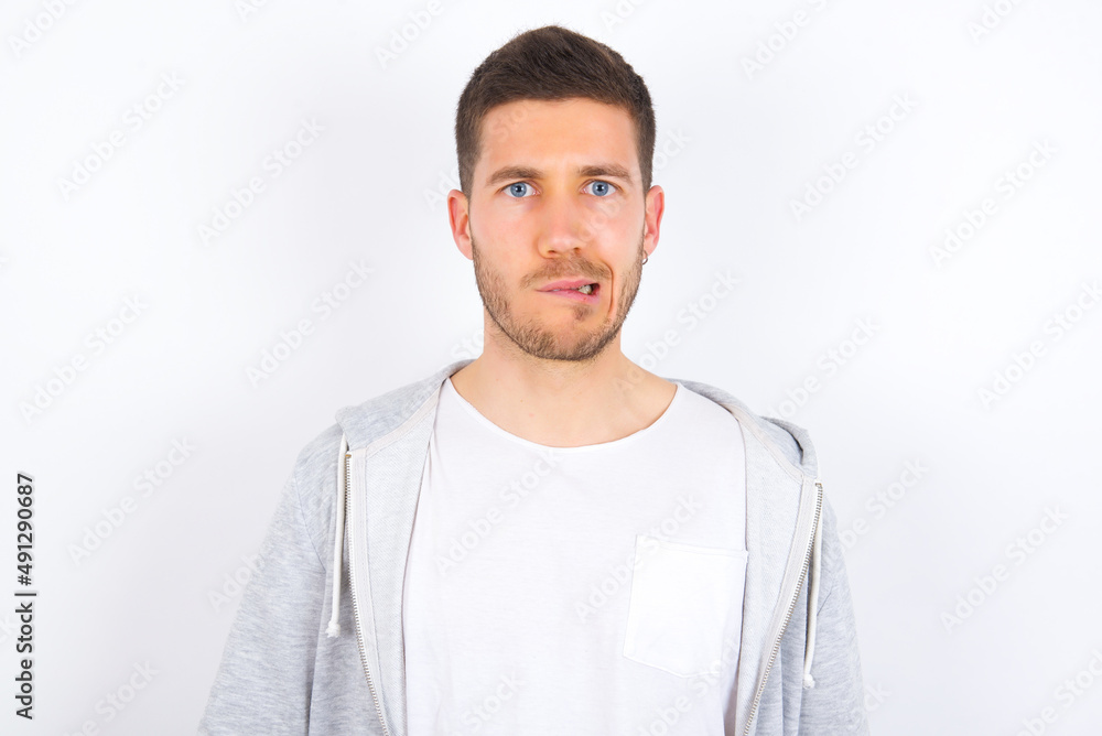young caucasian man wearing casual clothes over white background being nervous and scared biting lips looking camera with impatient expression, pensive. young caucasian man wearing casual clothes over white background being nervous and scared biting lips looking camera with impatient expression, pensive.