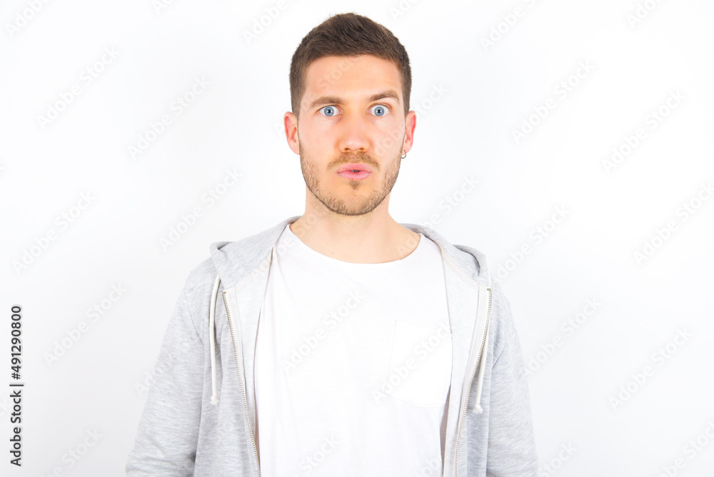 young caucasian man wearing casual clothes over white background expressing disgust, unwillingness, disregard having tensive look frowning face, looking indignant with something. young caucasian man wearing casual clothes over white background expressing disgust, unwillingness, disregard having tensive look frowning face, looking indignant with something.