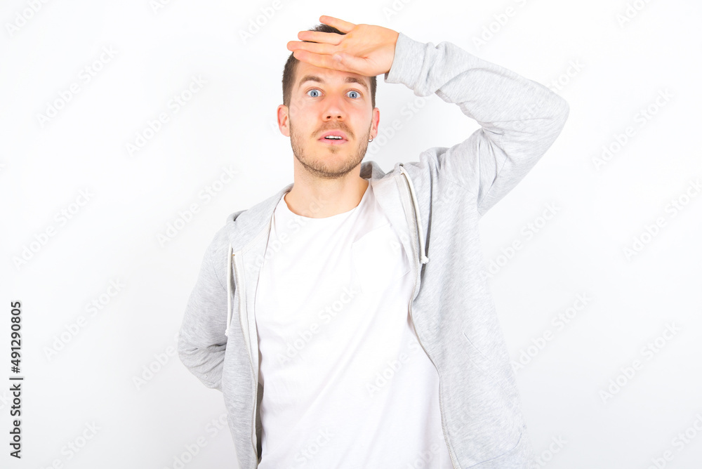 young caucasian man wearing casual clothes over white background  wiping forehead with hand making phew gesture, expressing relief feels happy that he prevented huge disaster. It was close enough
