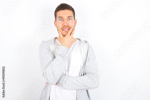 young caucasian man wearing casual clothes over white background  covering mouth with hands scared from something or someone bitting nails © Jihan