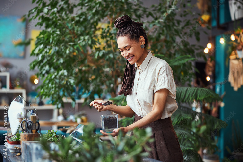 Floral designer looking at a soil container in her hand Floral designer looking at a soil container in her hand