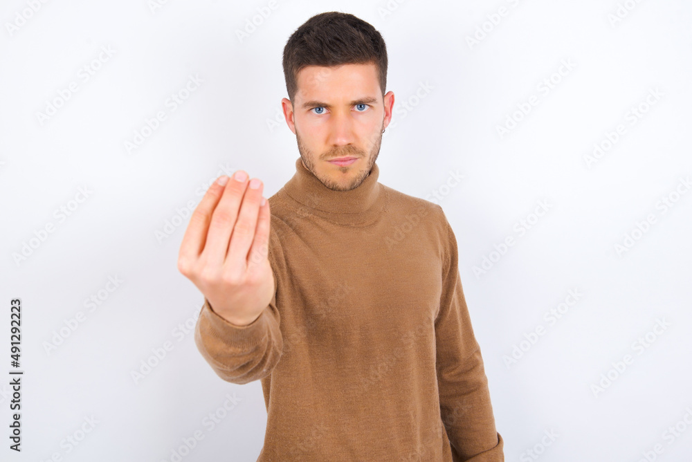 young caucasian man wearing knitted turtleneck over white background Doing Italian gesture with hand and fingers confident expression young caucasian man wearing knitted turtleneck over white background Doing Italian gesture with hand and fingers confident expression