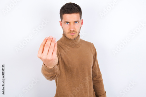 young caucasian man wearing knitted turtleneck over white background Doing Italian gesture with hand and fingers confident expression
