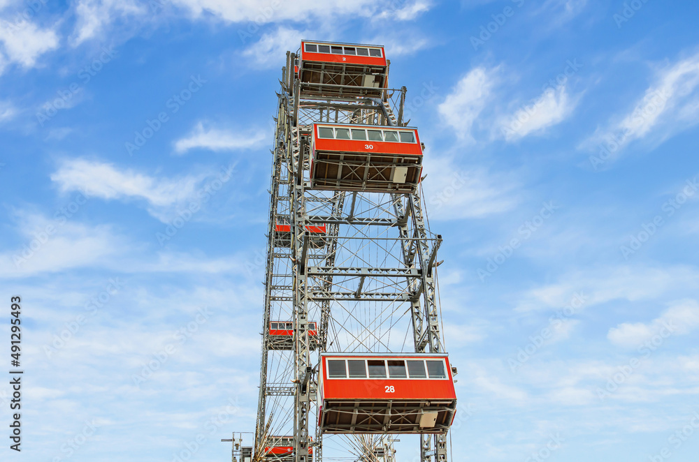 Fototapeta premium Ferris wheel with red cabins of the Prater amusement park in Vienna, Austria. Historical monument