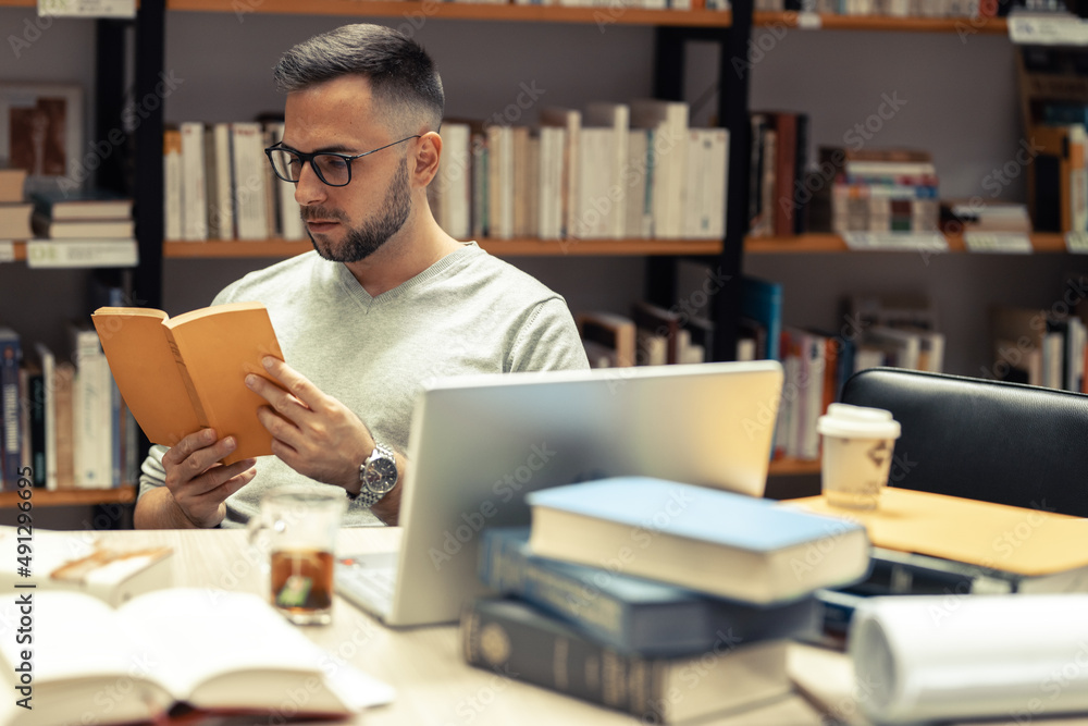 A male student studying in the campus library .He reads a book. A male student studying in the campus library .He reads a book.
