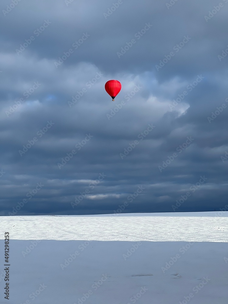Fototapeta premium Mongolfiera rossa vola nel cielo blu d’inverno