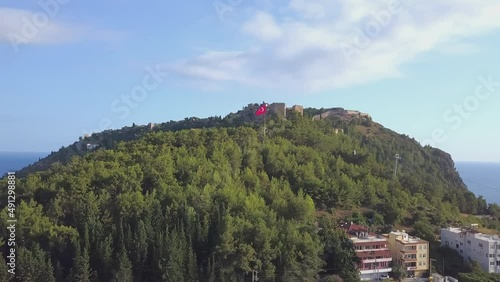 Top view of a city in Turkey on a hill during the day. CLIP. A beautiful suburb in the forests with a Turkish flag. Filmed on a quadcopter from above