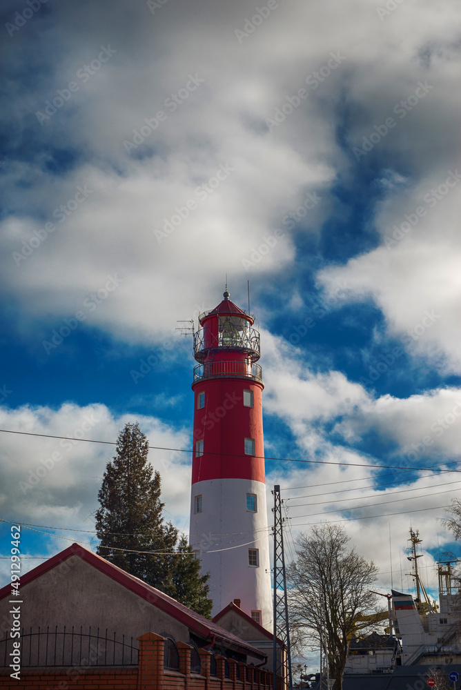 red and white historical Prussian lighthouse against a blue cloudy sky