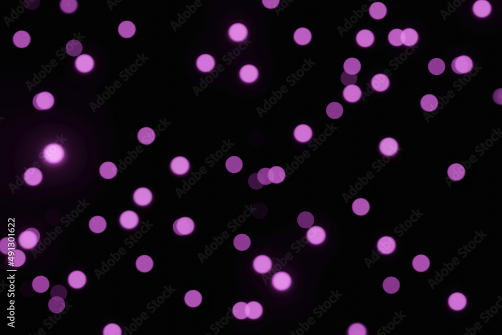 Defocused bokeh lights on black background, an abstract naturally blurred backdrop for Valentines Day or birthday party. Festive light texture. Violet blue garland in blur. Color 2022