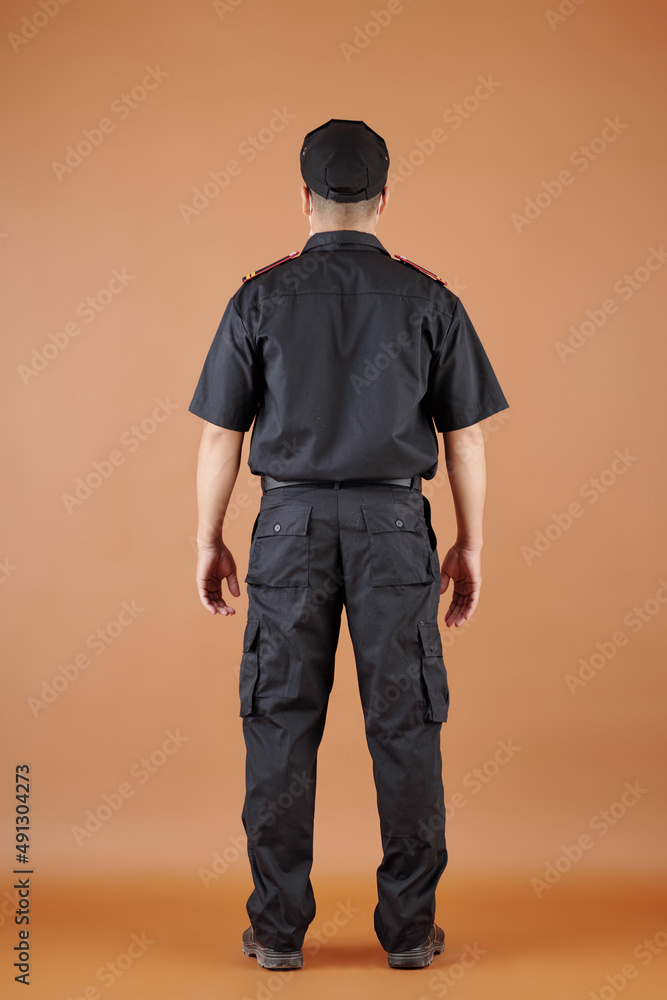 Confident security guard in black uniform, view from the back Confident security guard in black uniform, view from the back