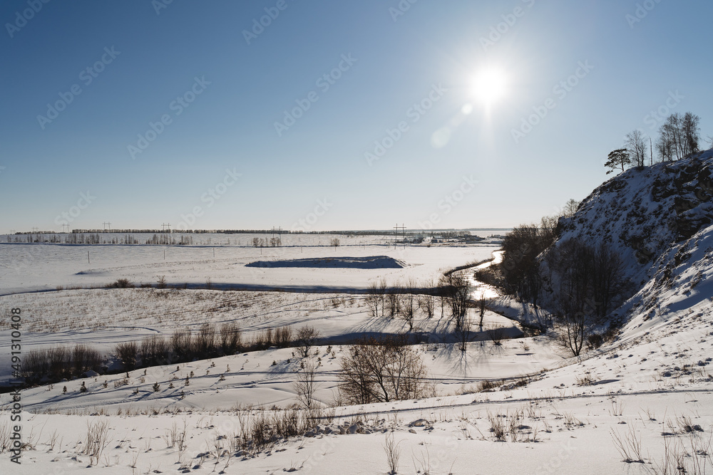 Bright sunlight against the sky. Winter landscape in Russia, blue lake Bashkortostan, Nature of the southern Urals.