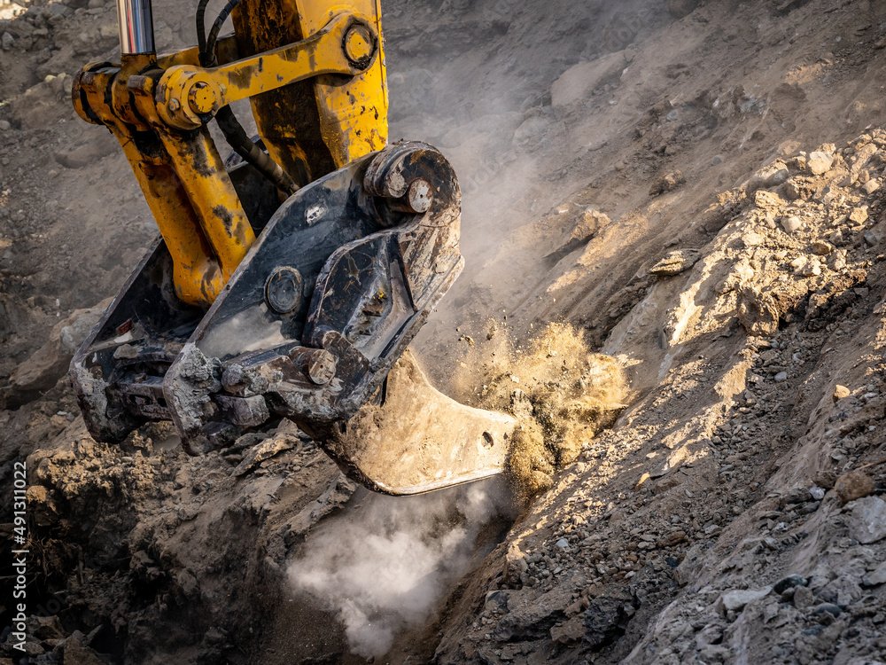 Excavator ripper attachment ripping frozen soils on construction site ...