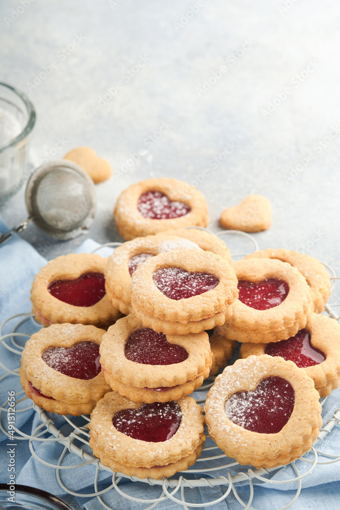 Traditional Linzer cookie with strawberry jam and powder sugar on light grey beautiful background. Top view. Traditional homemade Austrian sweet dessert food on Valentines Day. Holiday snack concept.