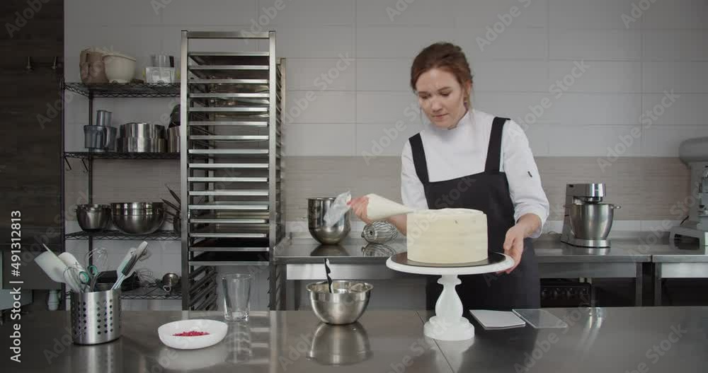 Using a pastry sleeve, the pastry chef applies cream to the cake Using a pastry sleeve, the pastry chef applies cream to the cake